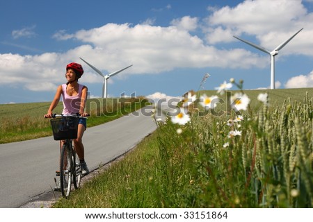 Woman relaxing and enjoying the sun on a bike trip in the countryside of Jutland, Denmark. Wind turbines in the background.