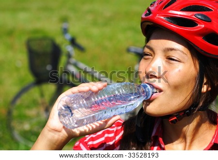 Beautiful young woman enjoying a bottle of water outdoors on a bike trip in Denmark.
