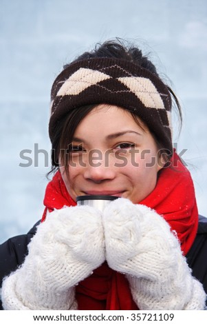 Cold winter woman getting warm drinking a hot drink. Ice wall background.