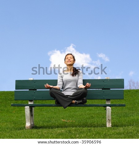 Meditation outside with head in the clouds. Beautiful mixed asian / caucasian young woman thinking in park.