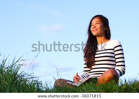 Woman studying outside in evening light with copy space. Beautiful mixed asian / caucasian woman.