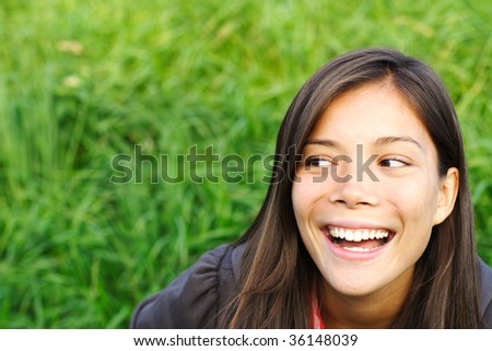 Ethnic model looking smiling at the copy space to the side, outside with out of focus green background