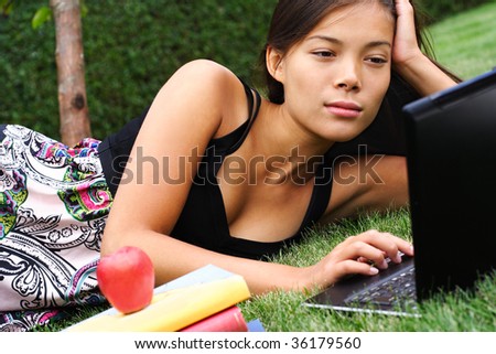 Student with laptop in the park. Beautiful mixed race caucasian / asian model.