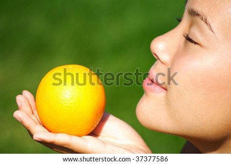 Orange. Pretty woman enjoying the smell of an orange during summer.