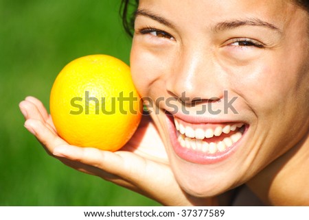 Orange. Cute young woman laughing holding an orange during summer.
