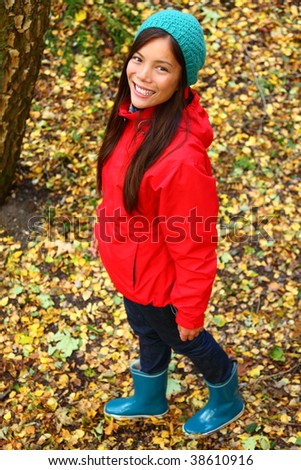 Autumn woman happy and smiling looking up at camera during a walk in the forest during fall