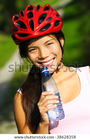 Exercise woman. Beautiful young woman enjoying a bottle of water outdoors during a bike trip
