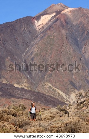 Woman hiking. Young asian walking with hiking poles / walking sticks during a hike / backpacking trip in the volcanic landscape in the national park on the volcano, Teide, Tenerife - copy space!