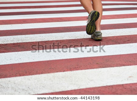 City Running. Closeup of woman running shoes in action on crosswalk in urban setting. Lots of copy space.