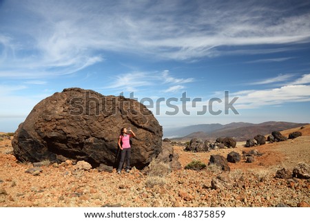 Tenerife - Woman hiking on Teide. A view of a female backpacker standing by one of the many big black Teide Eggs or in spanish: Los Huevos del Teide.