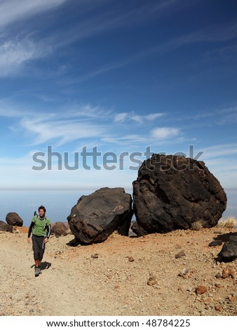 Man Hiking on Teide Tenerife. Man hiking / backpacking within the national park of Teide on Tenerife. A view of the hiking path showing many of the big black Teide Eggs. Blue sky for copy space.