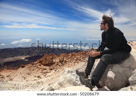 Hiking - Hiker enjoying view. Male hiker sitting and relaxing at the summit of the volcano  Teide on Tenerife.