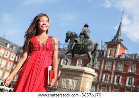 Madrid Woman tourist walking on Plaza Mayor Madrid Spain Beautiful woman in red dress Tourist attraction statue of Felipe III in the background Madrid Woman tourist walking on Plaza Mayor Madrid Spain Beautiful woman in red dress Tourist attraction statue of Felipe III in the background