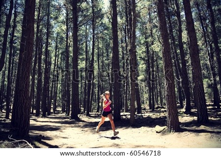 Running woman. Female runner running in forest. Beautiful Asian / Caucasian woman athlete jogging outdoors in beautiful forest with lots of mood / atmosphere and copy space.