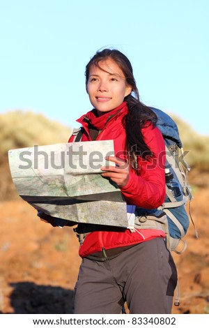 Hiking woman in nature holding map outdoors in nature. Smiling happy hiker in desert mountain landscape.