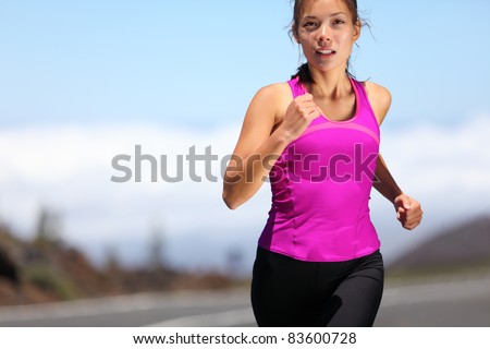 woman runner training for marathon. Female runner in sporty pink tank top jogging on mountain road. Beautiful young mixed race Asian Caucasian female fitness model outside.