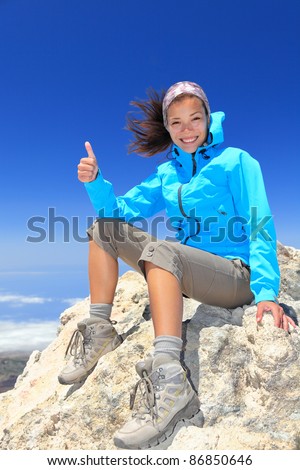 Hiker woman at mountain top summit enjoying view giving success thumbs up sign smiling happy of her hiking achievement. Beautiful happy smiling female hiker on the top of volcano Teide, Tenerife Spain