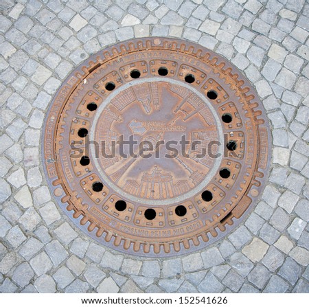 BERLIN, GERMANY - JULY 20, 2013: Berlin manhole cover featuring several city landmarks like Brandenburg Gate, Reichstag, Television Tower and logo of Berliner Wasserbetriebe