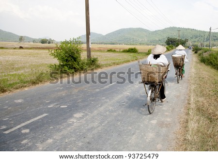 Two cyclists on a rural street in the Mekong Delta, Vietnam
