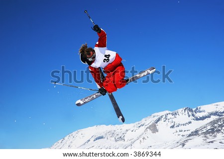 Freestyle skier jumps and crosses and grabs skis
