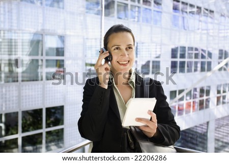 A young business woman in a suit calling in a glass elevator