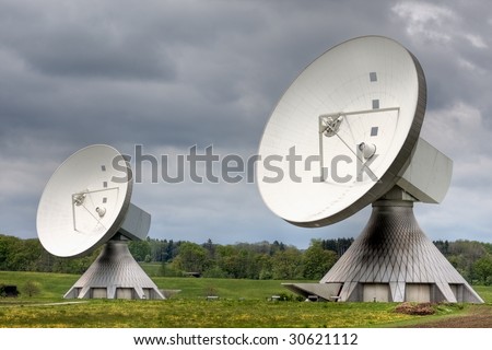 Two earth station satellite installations  - the type used for broadcasting. Poor weather.