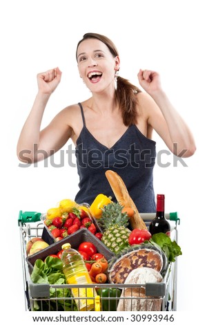 A woman with a full shopping cart happy to be shopping - punching the air on a white background