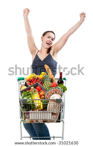 A woman with a full shopping cart happy to be shopping - punching the air on a white background