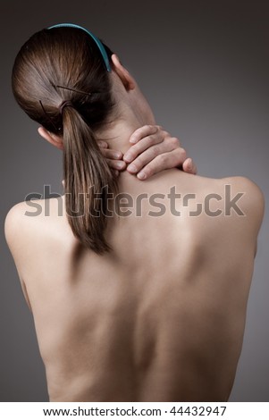 A woman holding her neck in pain with bare back