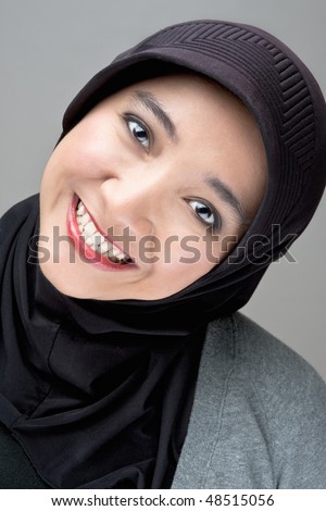 A young Islamic follower smiling wearing a traditional Hajib