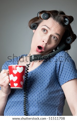 A woman in a domestic role gossiping on the phone with a mug.