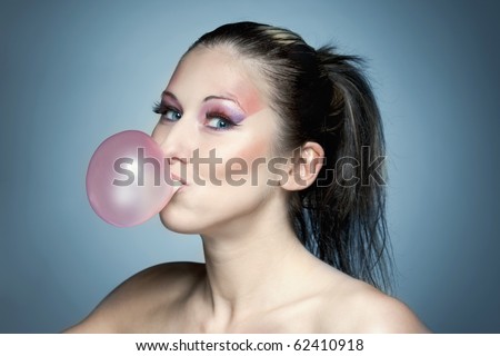 A happy fun young girl blowing bubble gum.