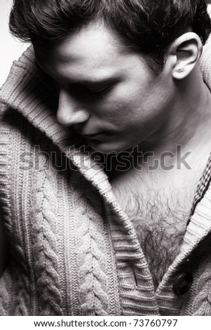 A handsome young man in a knitted sweater in dramatic lighting.