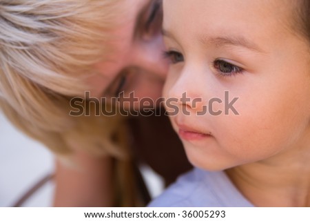 Mam to whisper in son\'s ear. Focus on child.
