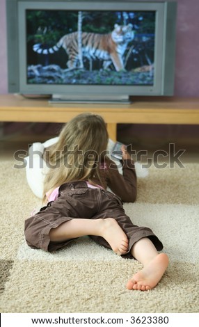 Four years old girl watching tv with remote on cozy carpet. tv screen contains my photographs as well.