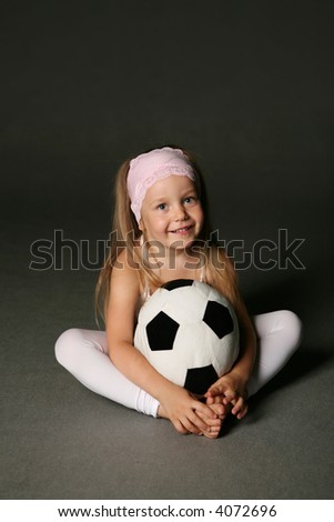 Little girl relaxing on a floor with soft soccer ball.