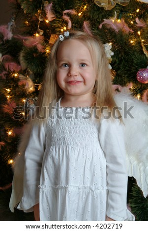 Little girl acting as an christmas angel. Christmas tree in a background.