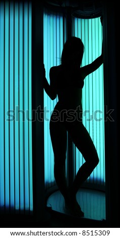 Young sexy female in a tanning cabin, shoot for shape against a light - full body length version.