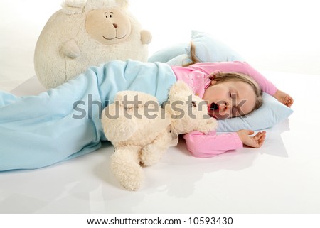 Five years old girl sleeping with her small friends. Studio shot on reflective floor.