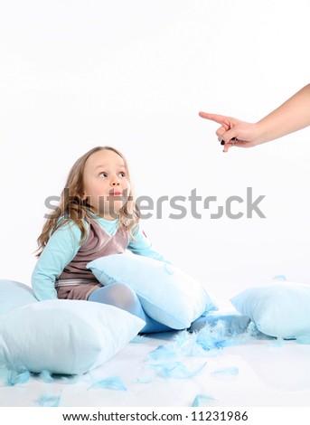 Five years old girl having fun with blue pillows and feathers on white background. Being told by mom to stop.