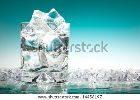 Glass of iced water in a pool of water and ice in turquoise