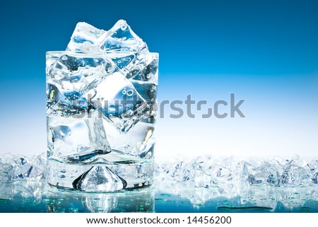 Glass of iced water in a pool of water and ice in blue
