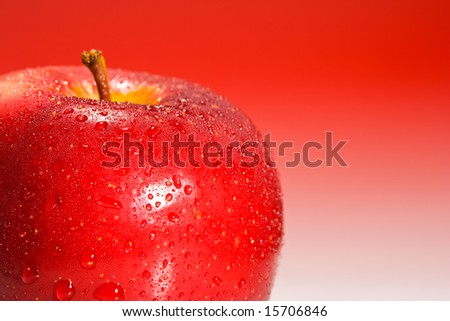 Shinny red apple on red gradient background with water drops