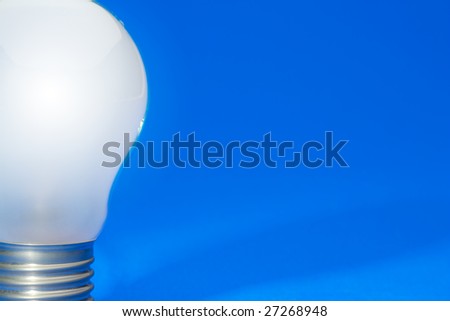 Illuminated light bulb on blue studio lit background