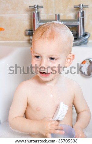small boy in the bath playing with a hair brush