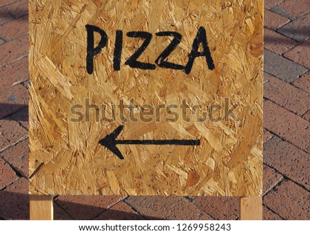 Pizza sign with direction arrow on wooden board