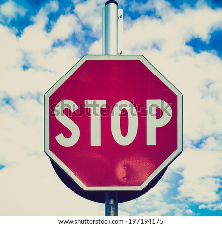 Vintage retro looking Stop traffic sign over blue sky with clouds