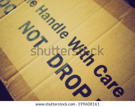 Vintage retro looking Fragile Handle with Care Do not drop label on a corrugated cardboard box
