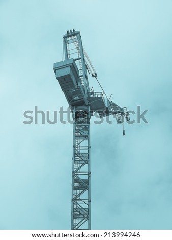 Building crane in a construction site over blue sky - cool cyanotype