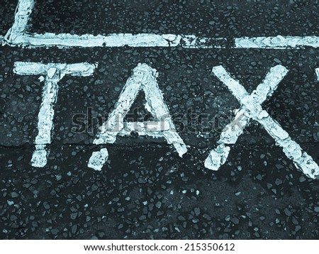 Tax sign in yellow over gray asphalt background - cool cyanotype